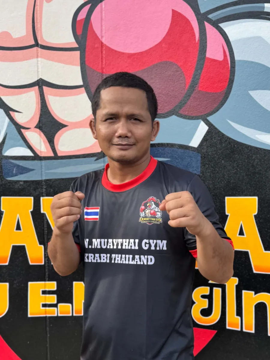 Eak, coach at E.N. Muaythai Gym, in front of the gym mural in Ao Nang