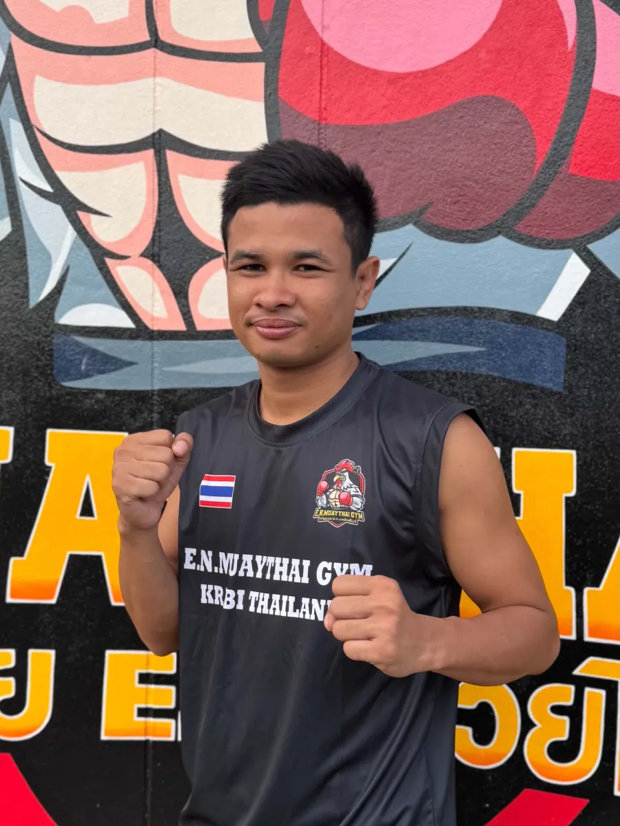 Ken, coach at E.N. Muaythai Gym, in front of the gym mural in Ao Nang
