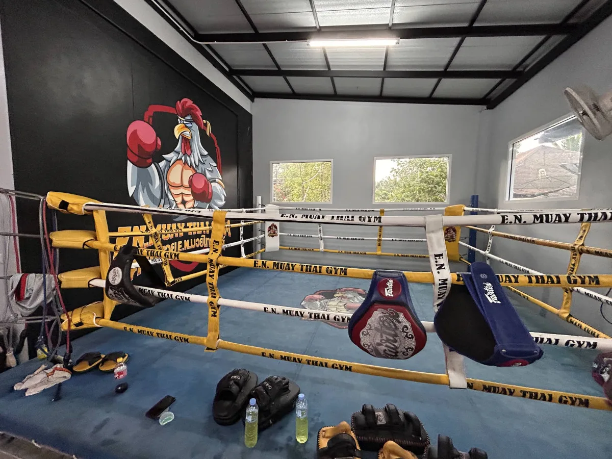 E.N. Muay Thai Gym branded ring with the gym's rooster mural on the wall behind it